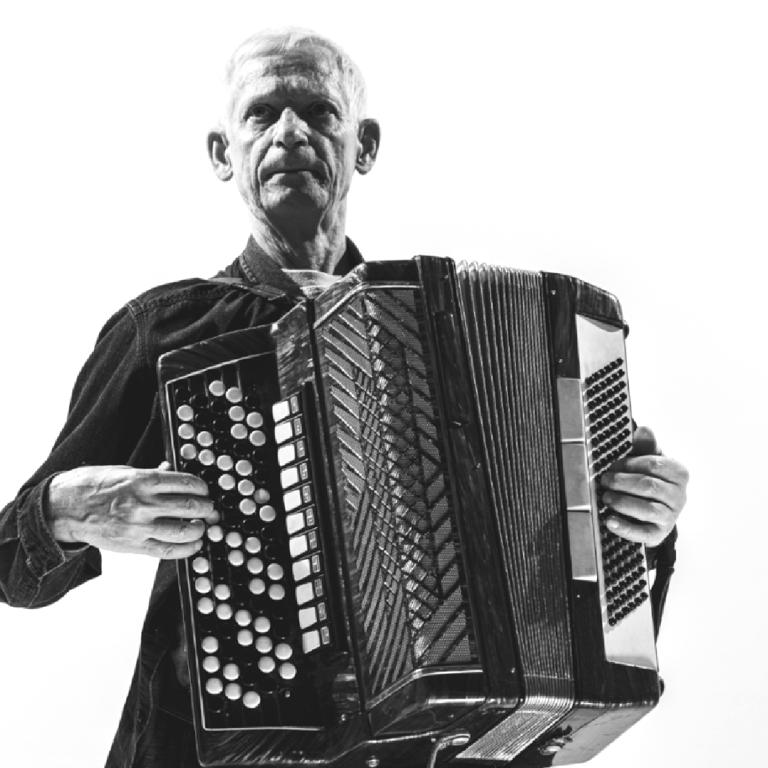 Ein alter Mann, der mit Hoffnung in den Augen ein Akkordion spielt